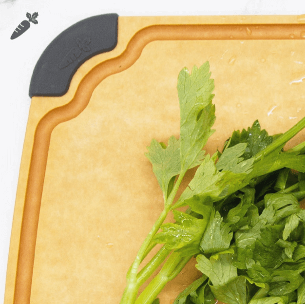 Close-up of an Elihome wood fiber cutting board with color-coded gray silicone corner for vegetables, featuring deep juice groove, shown with fresh celery