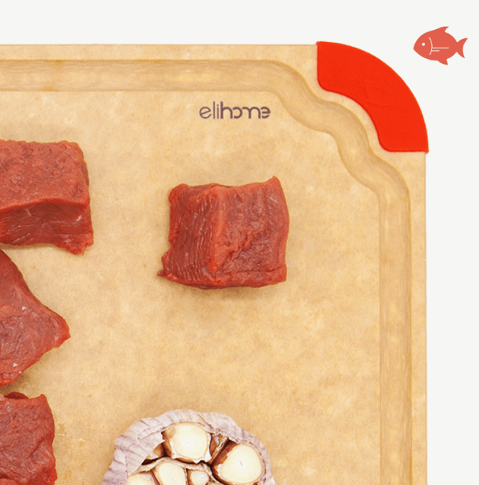 Close-up of an Elihome wood fiber cutting board with color-coded red silicone corner for meat and seafood, featuring juice groove, shown with raw beef and garlic.