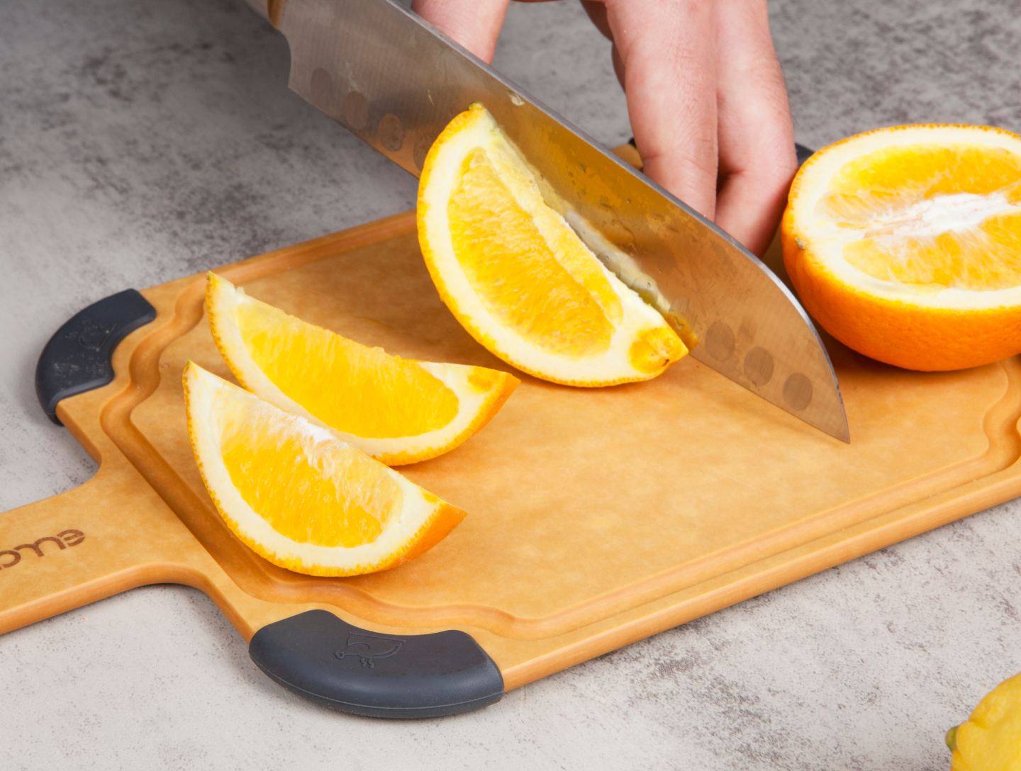 Slicing fresh orange wedges with a sharp knife on Elihome's knife-friendly wood fiber cutting board with non-slip corners
