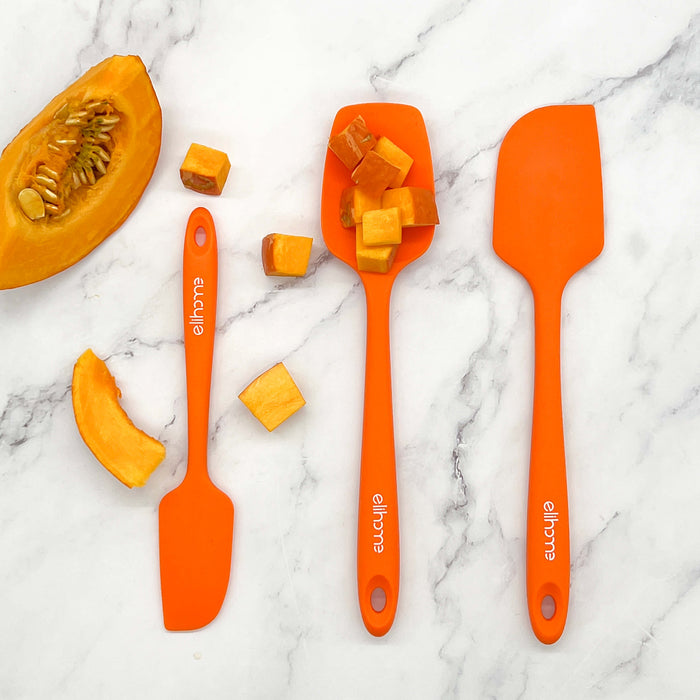 Elihome orange silicone spoonula holding pumpkin cubes, displayed with matching spatulas. The warm and lively orange set is perfect for autumn baking and cooking.