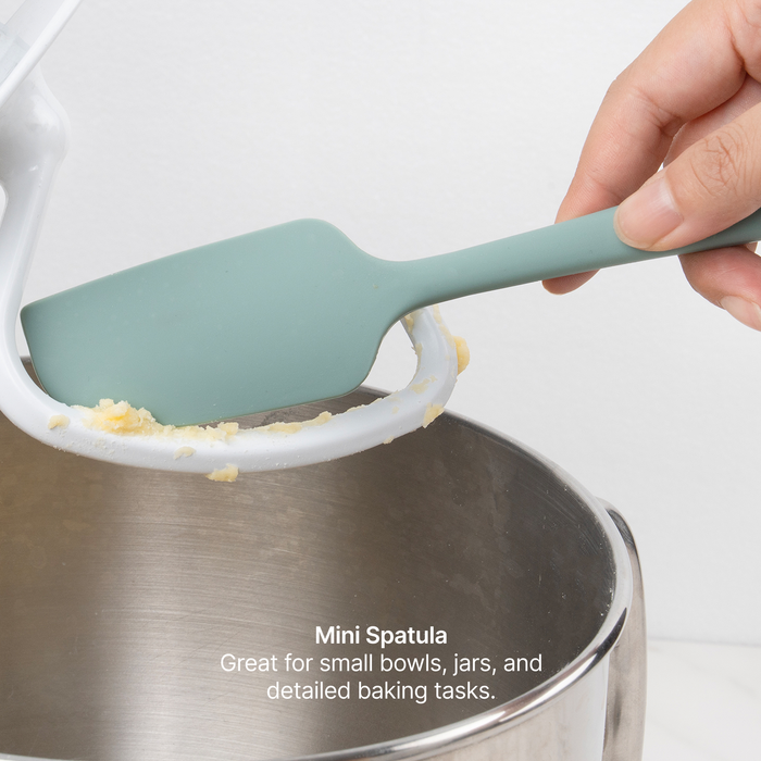 Hand using the Elihome x Peanuts Mini Spatula to scrape batter from a stand mixer bowl, great for small bowls, jars and detailed baking tasks