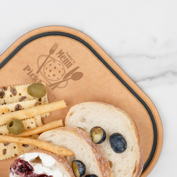 Crackers, breadsticks, sourdough slices, olives, and berry jam served on an Elihome pickleball paddle board engraved with Today's Menu: Pickleball